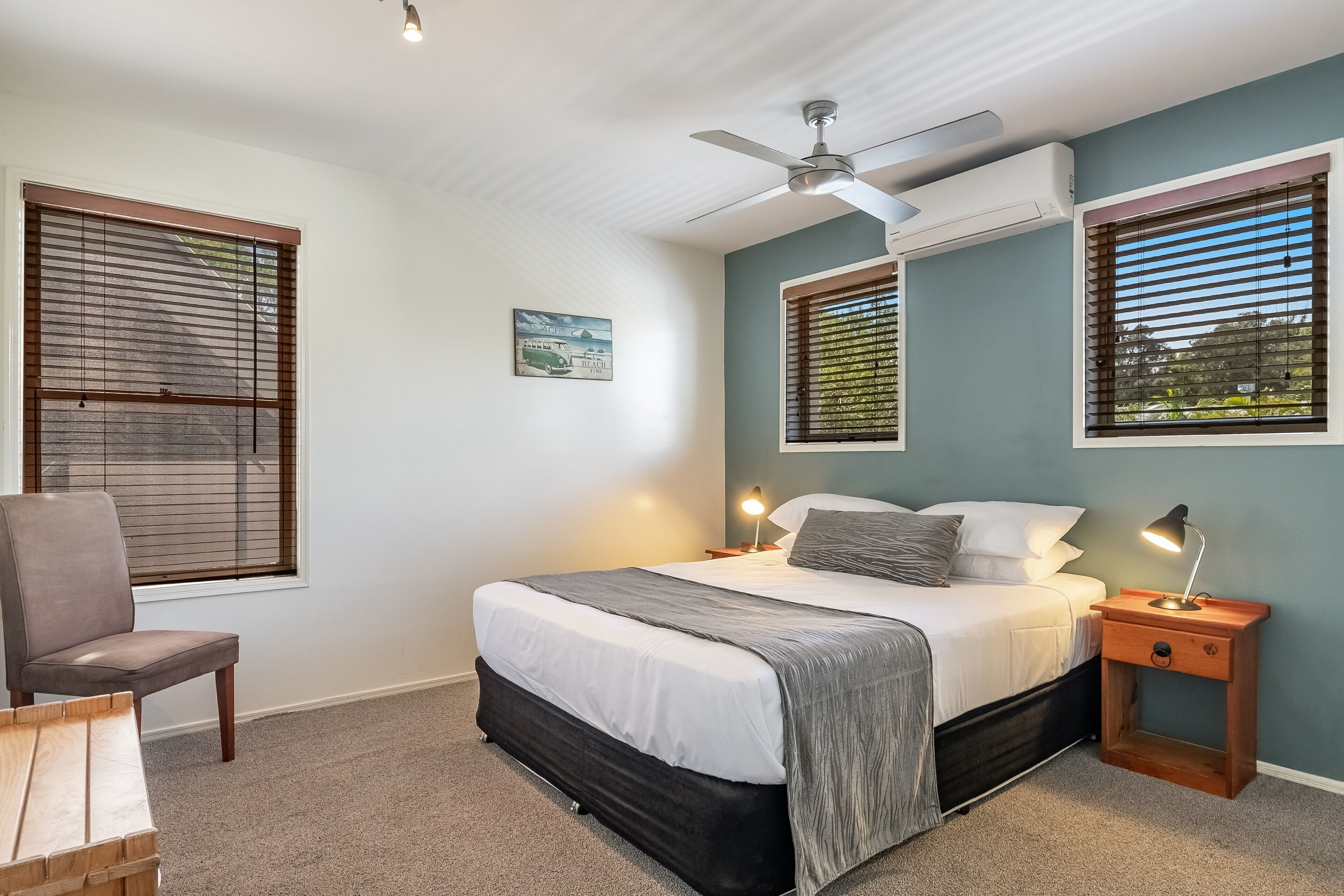 A bedroom with a bed, a chair, a nightstand, and a ceiling fan.