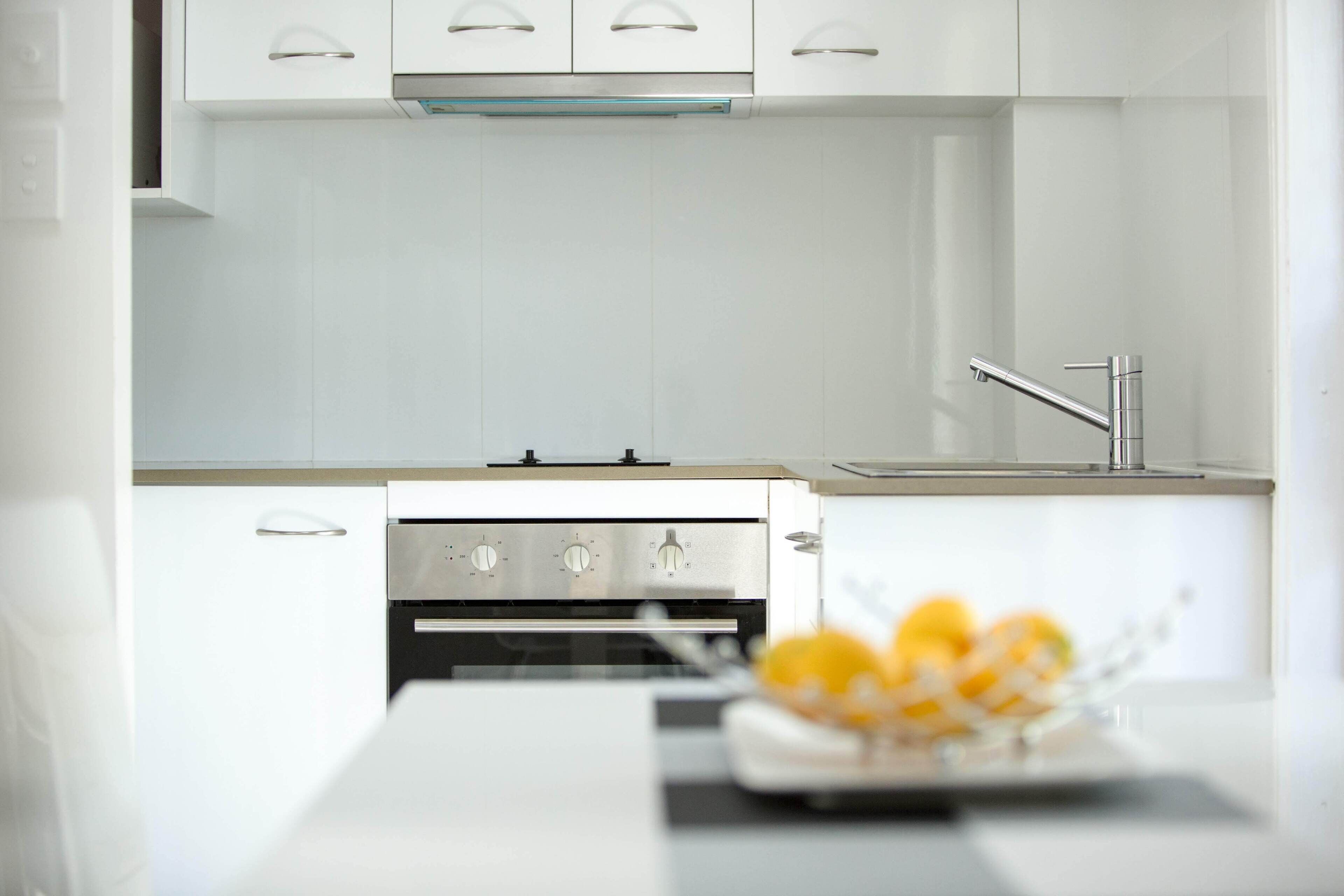 Een moderne keuken met witte kastjes, een roestvrijstalen afzuigkap en een ingebouwde oven.