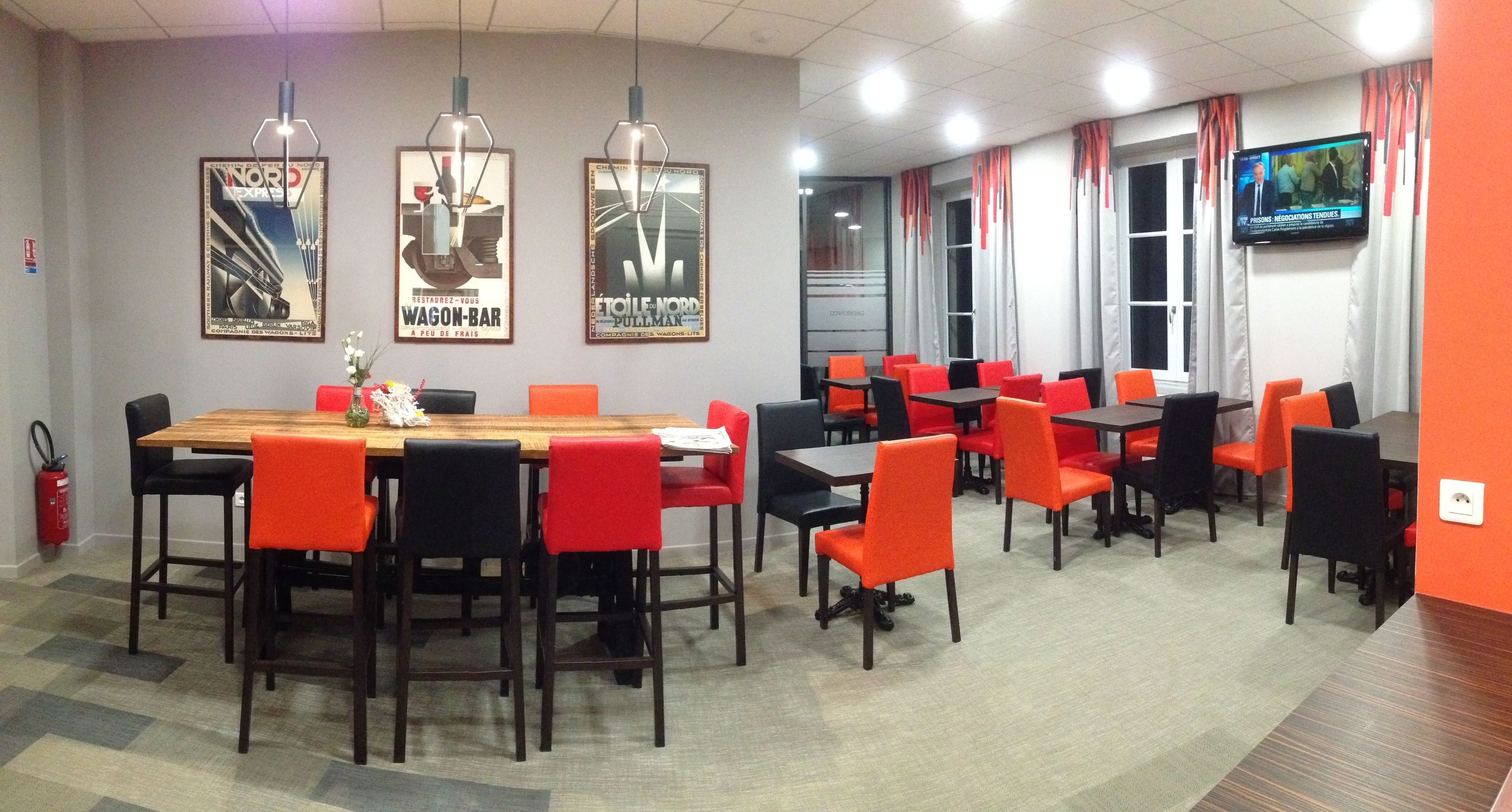 A conference room with a long table and multiple chairs, a fire extinguisher, and framed posters on the wall.