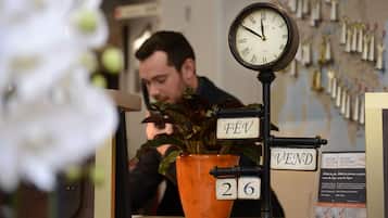 A vintage clock with Roman numerals, a sign with the word "VEND", and a potted plant with a number sign.