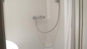 Ein kleines, kompaktes Badezimmer mit Toilette, einer Dusche mit Duschhandstück und einer Duschvorhang.