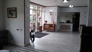 A spacious room with a wooden cabinet, a motorcycle, and a reception desk. - Los Olmos (Lugo)