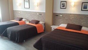A hotel room with two beds, each with dark bedding and orange accents. There are wall-mounted lights and framed pictures above the beds. - Los Olmos (Lugo)