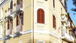 Un edificio en esquina con varios balcones, una puerta visible y una señal de calle.