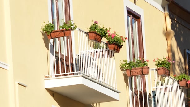 Un edificio con varios balcones, cada uno con barandillas de madera y macetas con plantas.