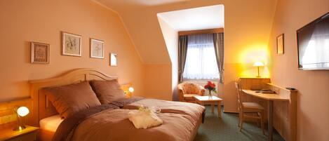 A hotel room with a large bed, a desk, a chair, and a television.