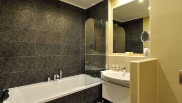 A modern bathroom with a large bathtub, a sink, and a mirror.