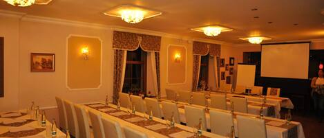 Un salón de conferencias con mesas largas, sillas y candelabros.