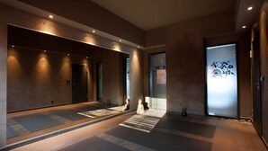 Un interior moderno con un largo pasillo, paredes reflectantes y un suelo con diseño.