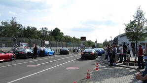 Una calle bordeada de coches aparcados y una multitud de gente.