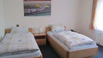 Ein Hotelzimmer mit zwei Betten, einem Nachttisch mit Lampe, einem Telefon und einem Poster einer Rennveranstaltung an der Wand.