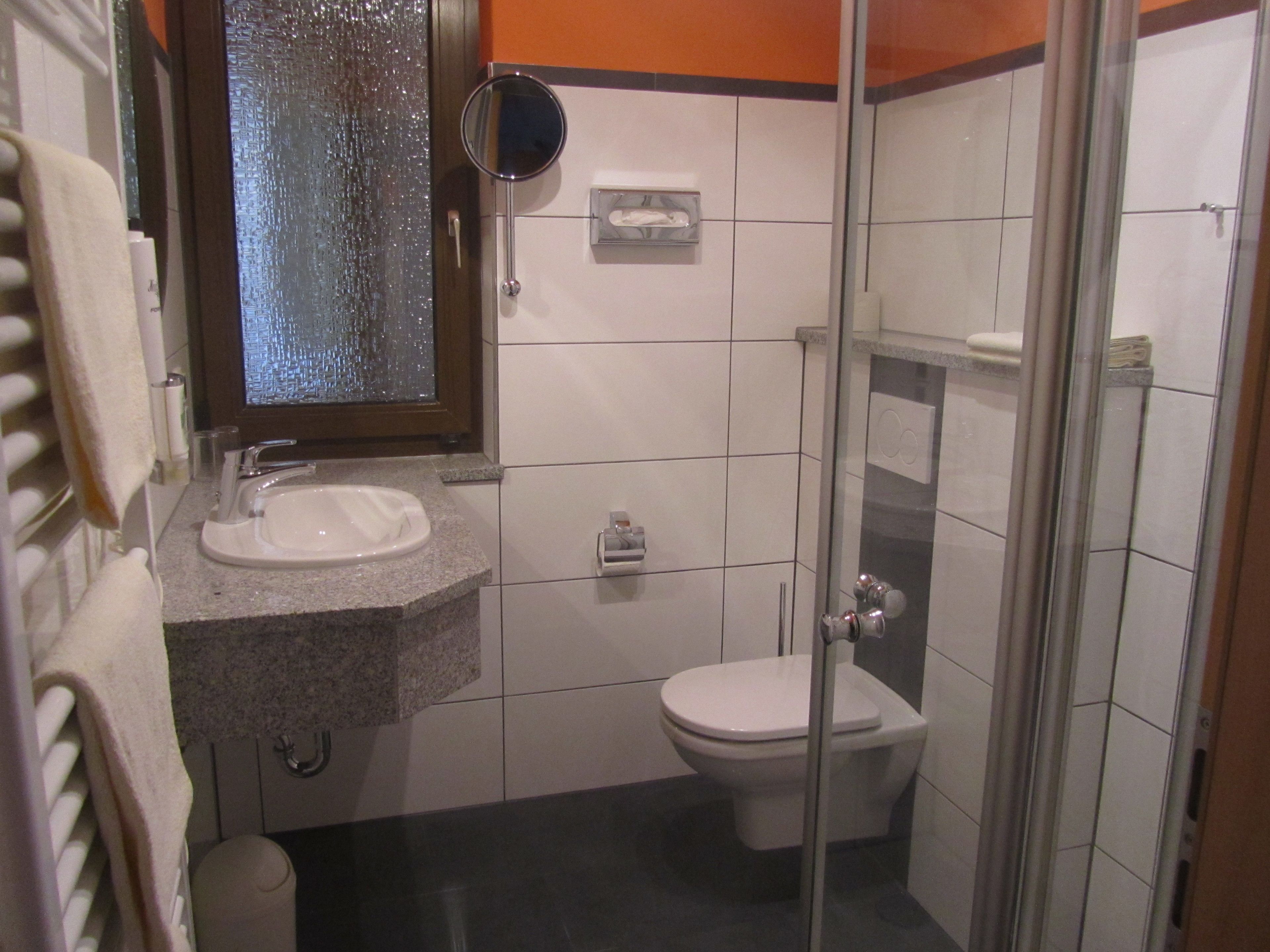 Un baño con lavamanos, inodoro y cabina de ducha de vidrio.