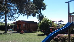 Un parque infantil con un tobogán azul y un columpio.
