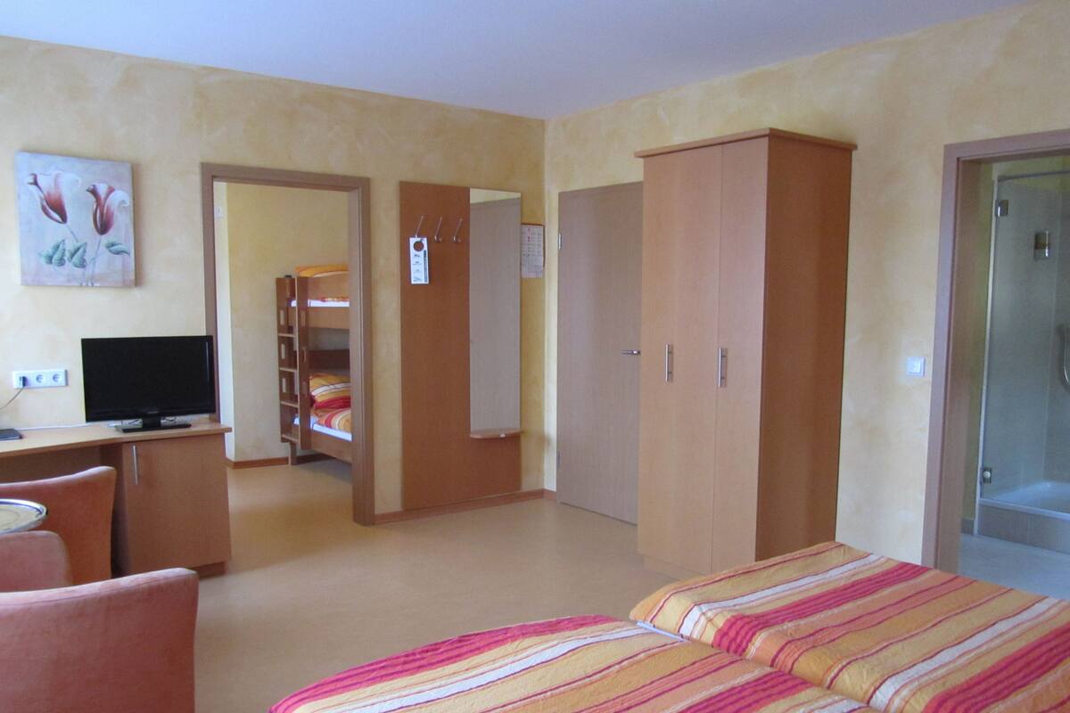 Ein Hotelzimmer mit einem Bett, einem Schreibtisch mit Computer, einem Kleiderschrank und einem Duschbereich.