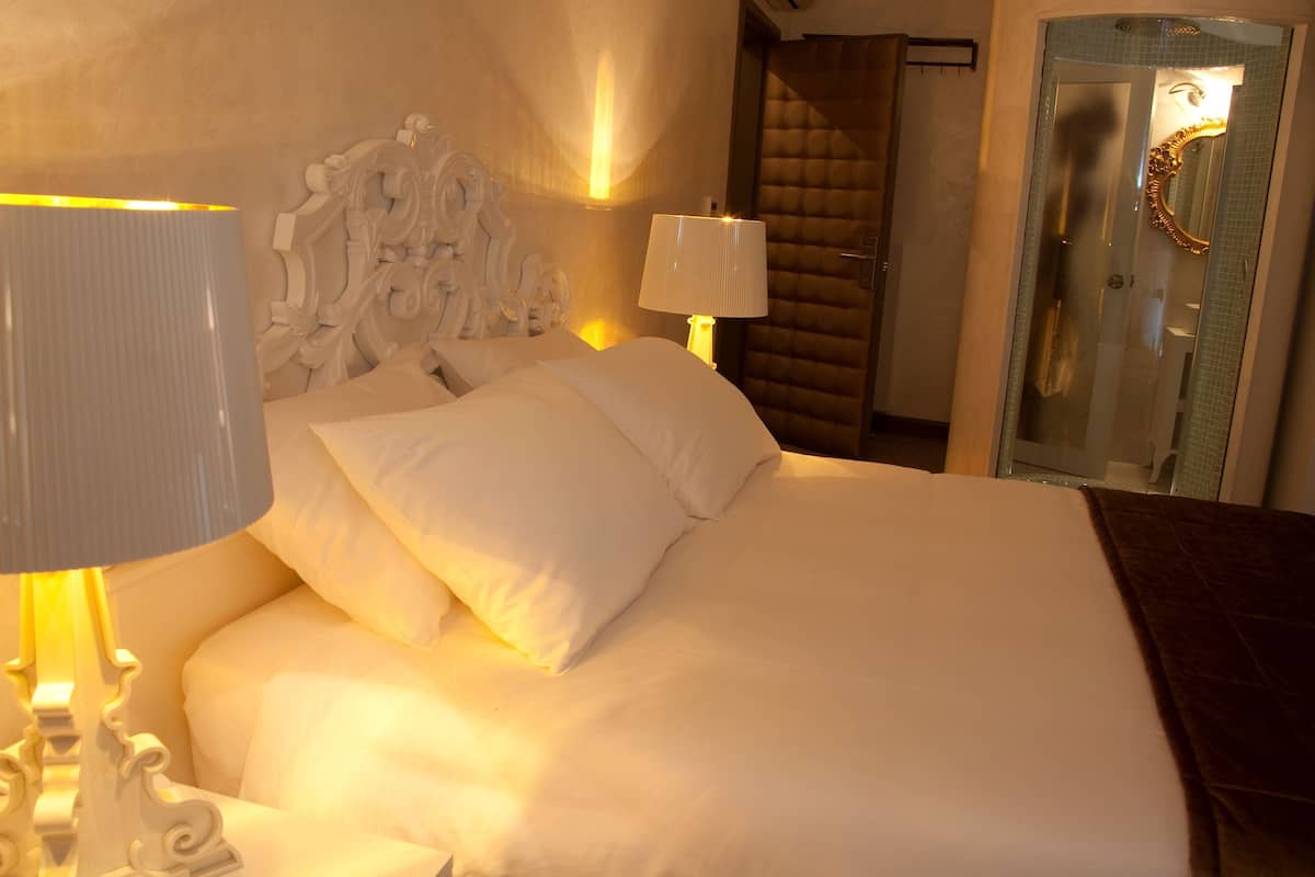 A neatly made bed with white linens, two bedside lamps, and a decorative headboard.