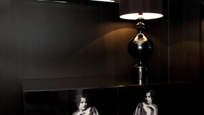 A modern room with a large mirror, a black lamp, and a framed photograph of a person.