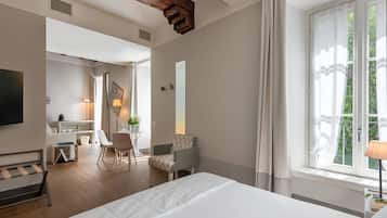 Una habitación de hotel moderna con una cama grande, un escritorio con una silla, una mesita con una lámpara y una ventana con cortinas.