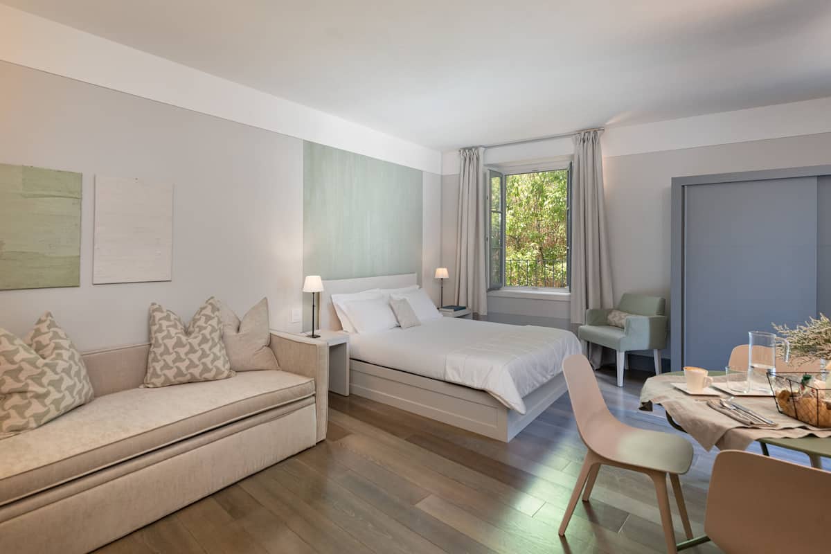 Un dormitorio moderno con cama, mesitas de noche, sofá, mesa de comedor y una silla.