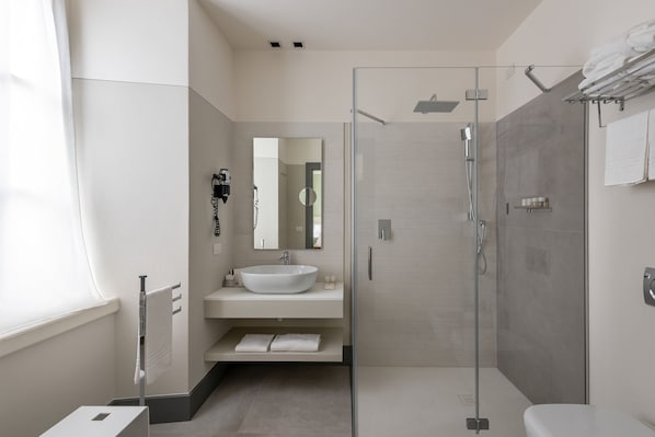 Un baño moderno con ducha de vidrio, un lavabo blanco y un espejo grande.