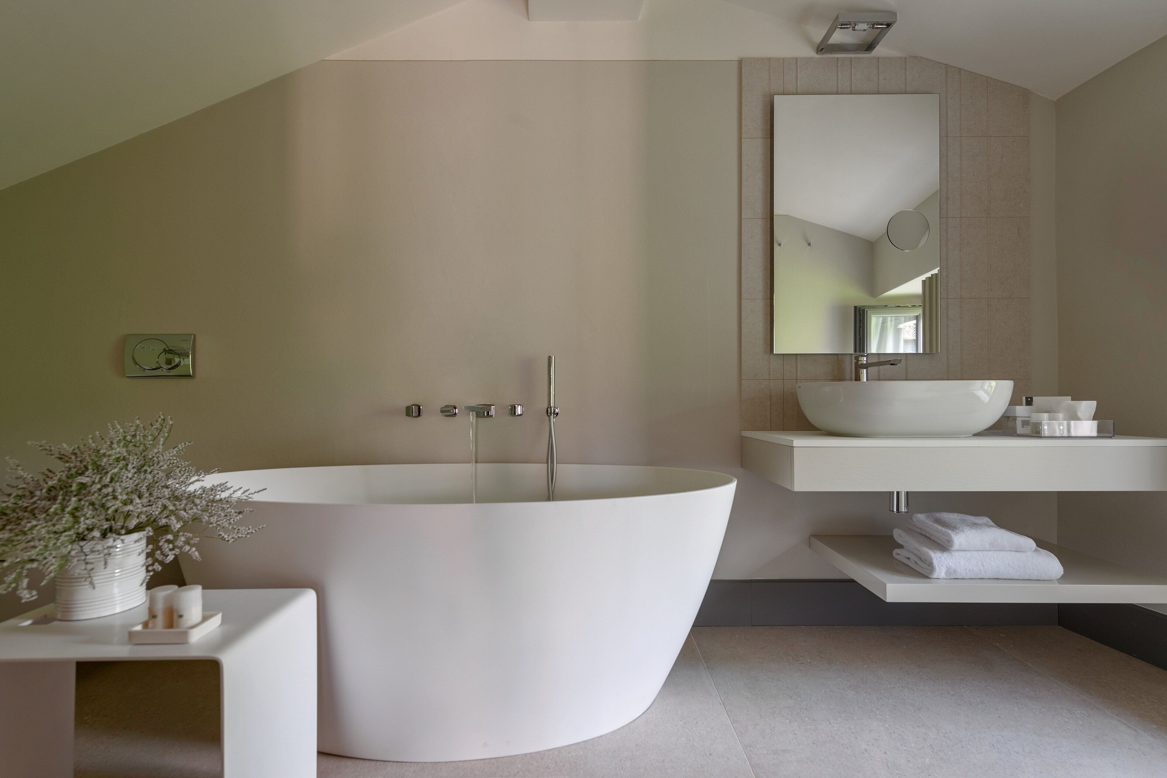 A modern bathroom with a freestanding bathtub, a large mirror, and a white sink.