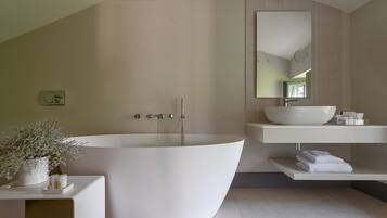 A modern bathroom with a freestanding bathtub, a large mirror, and a white sink.