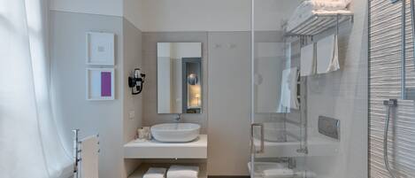 A modern bathroom with a large mirror, a vessel sink, a glass-enclosed shower, and neatly arranged towels.