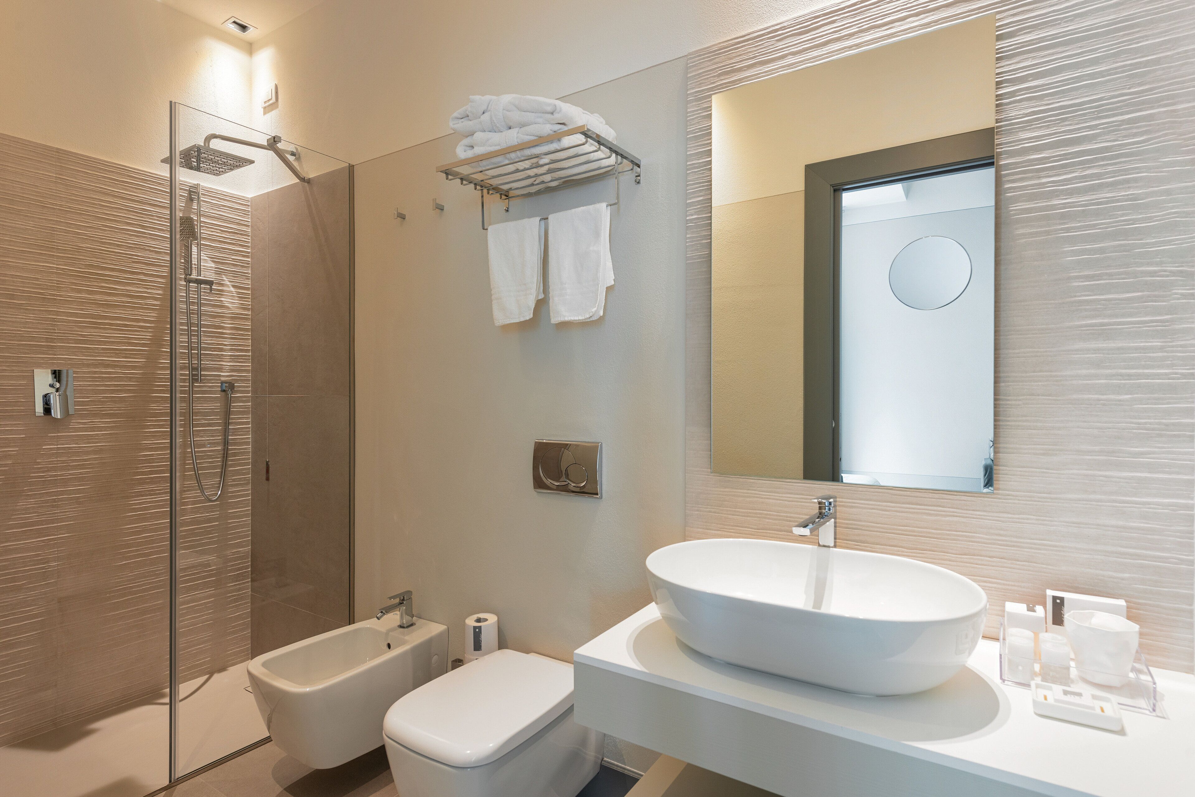 A modern bathroom with a glass shower enclosure, a white sink, and a towel rack.