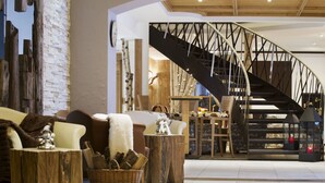 A modern interior with a curved staircase, rustic furniture, and a cozy fireplace. - Sporthotel Romantic Plaza (Pinzolo)