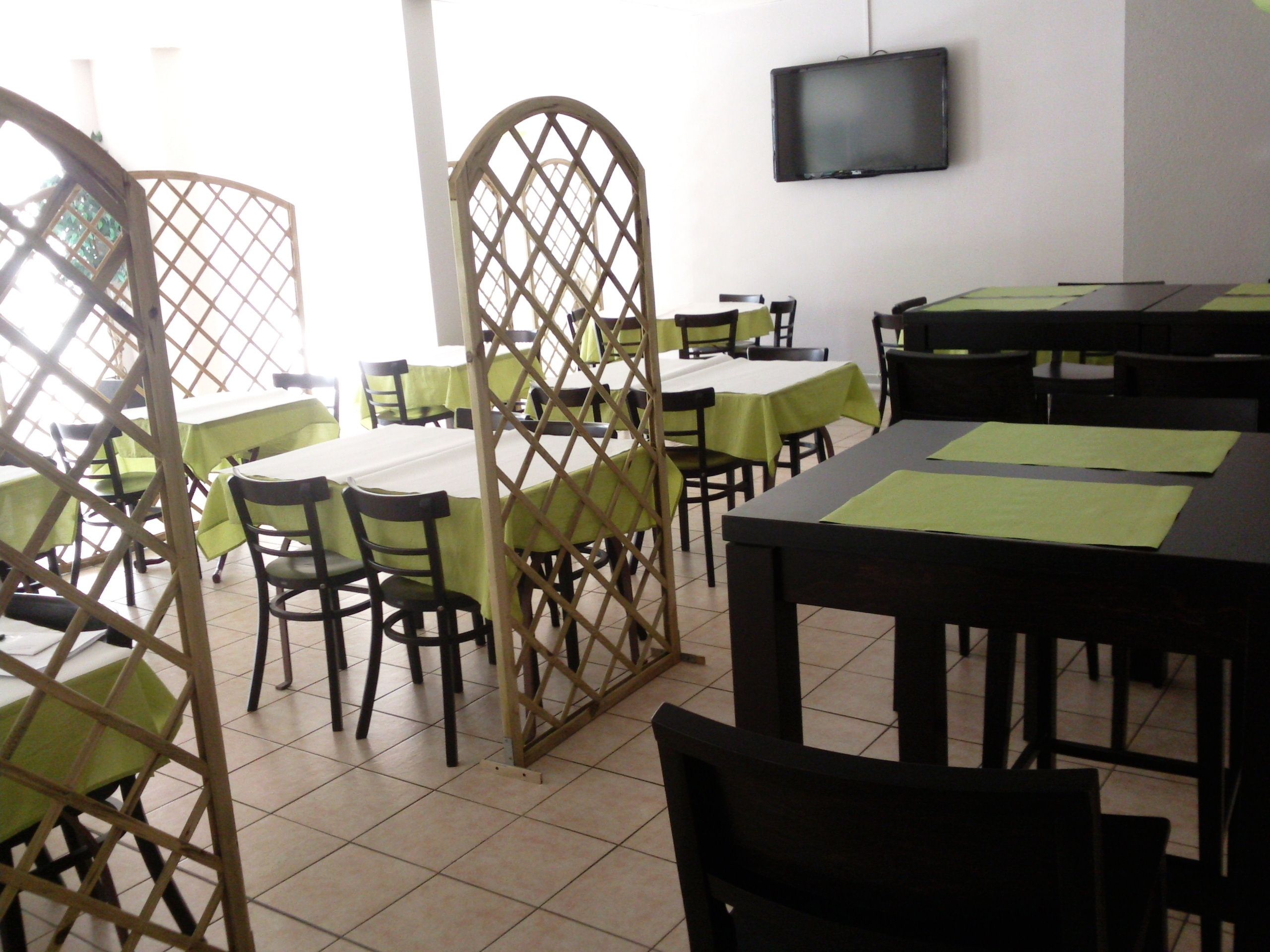 Un espace repas avec des tables et des chaises, un téléviseur fixé au mur et une cloison en bois.