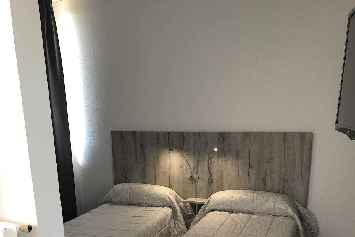 A room with two beds, a wooden headboard, and a dark carpet.
