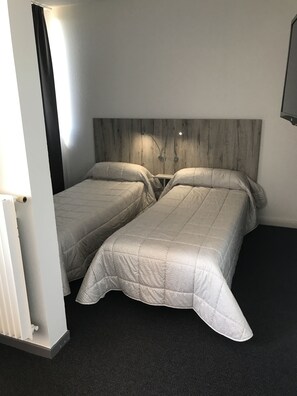 A room with two beds, a wooden headboard, and a dark carpet. - Hôtel-Résidence les Aiguades (Port-de-Bouc)