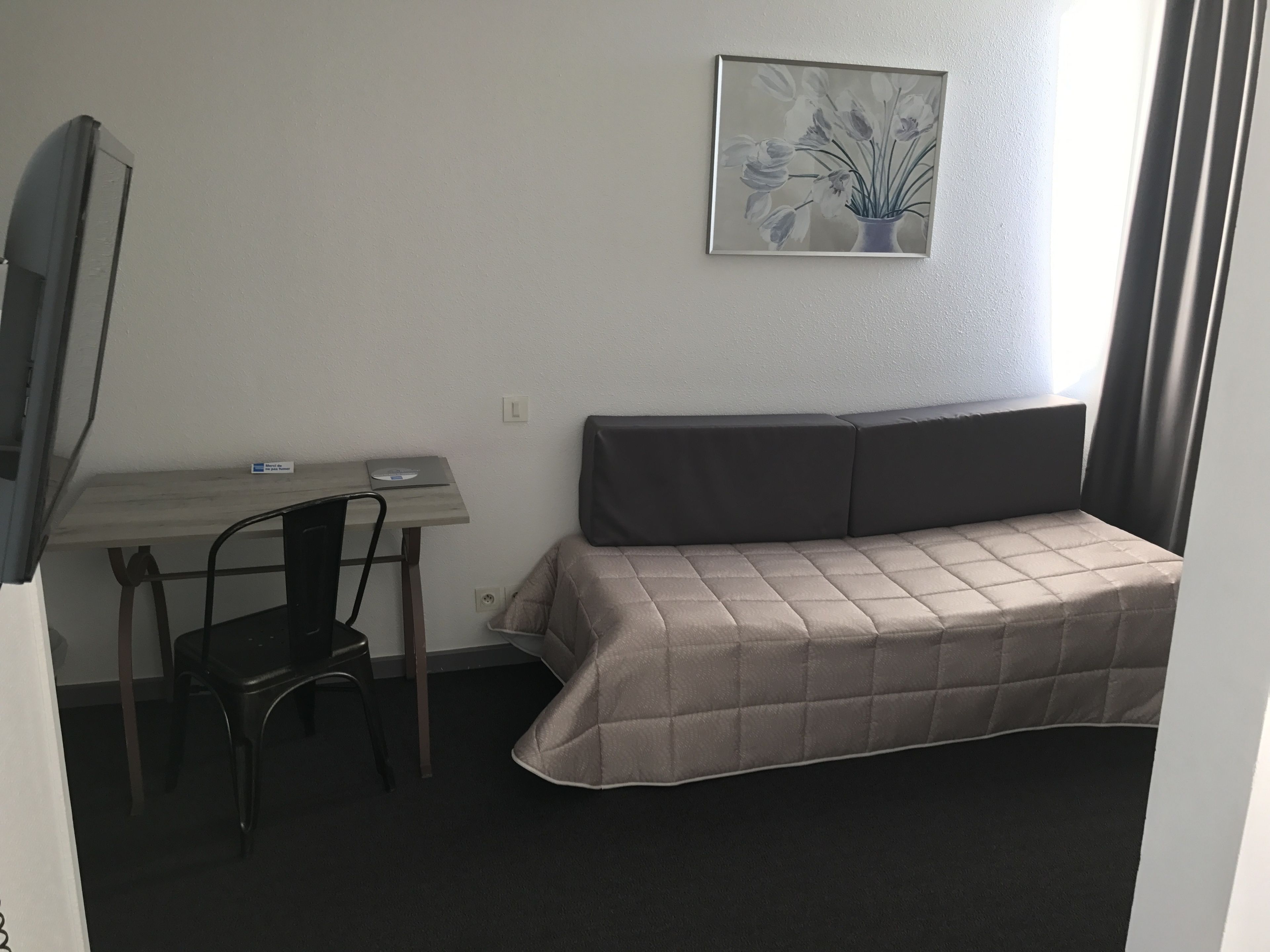 Una habitación pequeña con cama, escritorio y silla.
