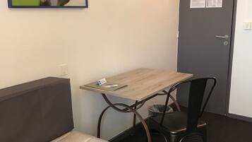 Une chambre d’hôtel avec un lit, un bureau, une chaise et une porte sur laquelle est affiché un avis.