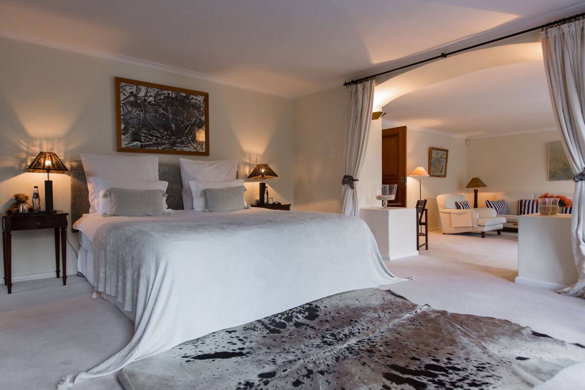Un dormitorio amplio con una cama grande, dos mesitas de noche, una silla y un sofá.