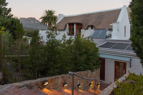 A white building with a thatched roof, stone walls, and solar panels.
