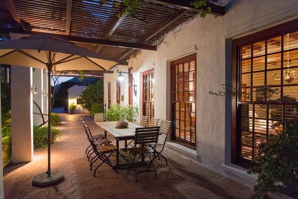 An outdoor patio with a table and chairs, a pergola, and a view of a mountain in the background.