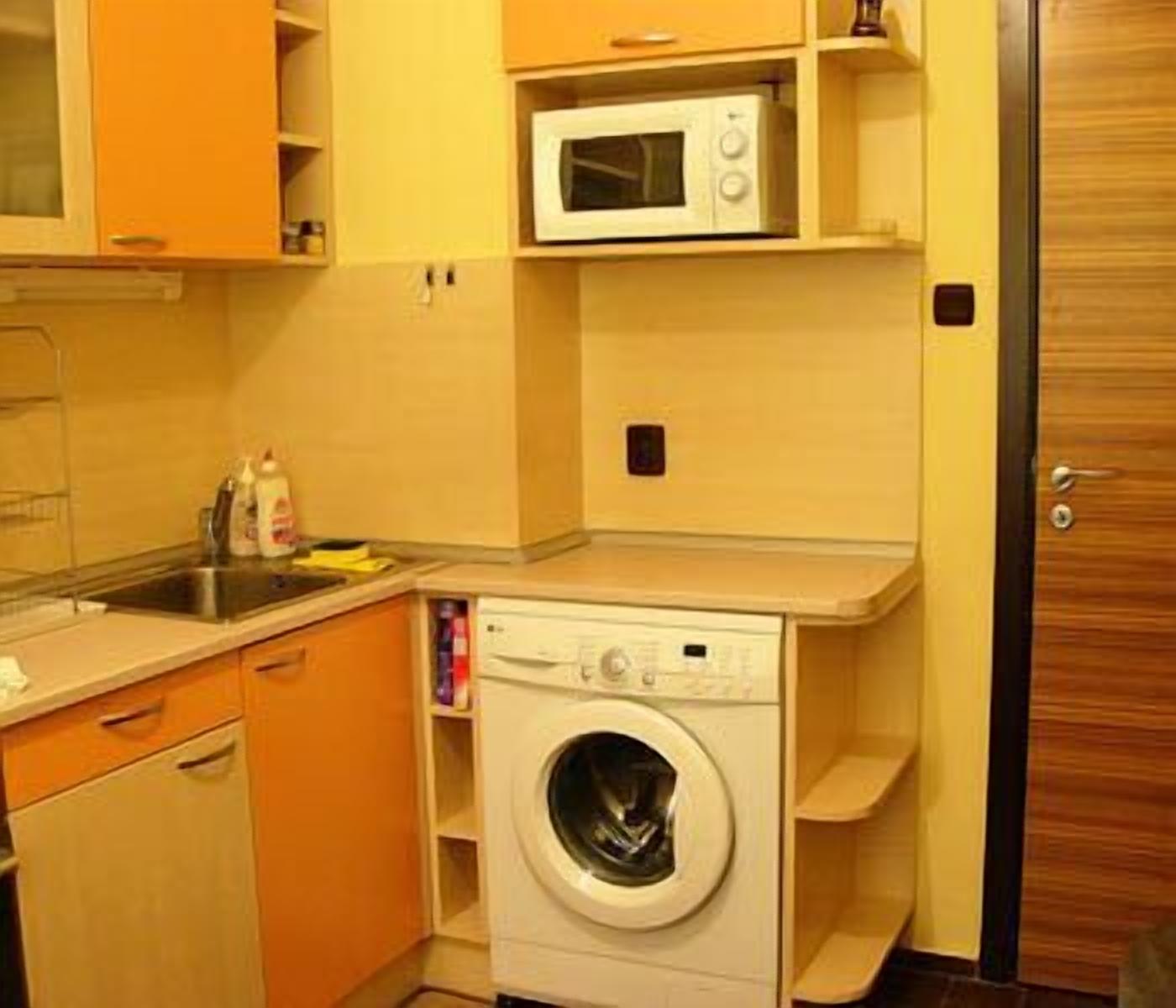 Una cocina compacta con lavadora, microondas y fregadero.
