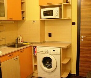 A compact kitchen with a washing machine, a microwave, and a sink.