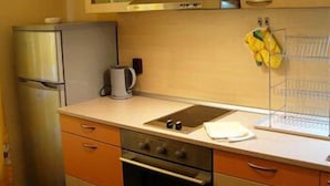 A compact kitchen with a refrigerator, oven, and a kettle on the countertop. - BUZ Apart Sofia (Sofia)