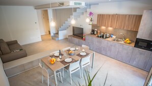 Una cocina moderna con comedor, electrodomésticos integrados y una escalera que sube a otro nivel.