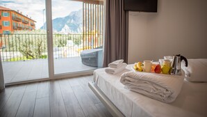 Habitación de hotel con cama, televisión de pantalla plana y balcón con vista a la montaña.