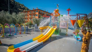 Parque acuático con un tobogán multicolores y diversas estructuras para jugar en el agua.