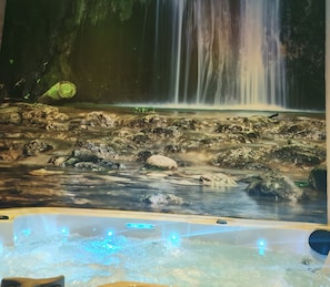 Un jacuzzi con vista a una cascada.