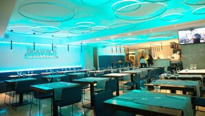 A restaurant with a modern interior, featuring circular ceiling lights and a visible kitchen area. - Hotel Centro Los Braseros (Burgos)