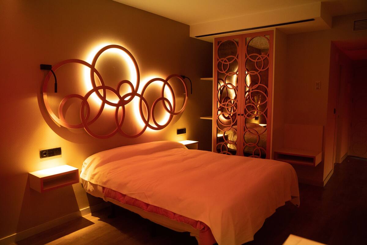 A modern bedroom with a bed, a wall-mounted light fixture, and a decorative cabinet.
