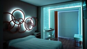 A modern hotel room with a bed, a desk, and a chair. There is a wall art piece and a window with a view. - Hotel Centro Los Braseros (Burgos)