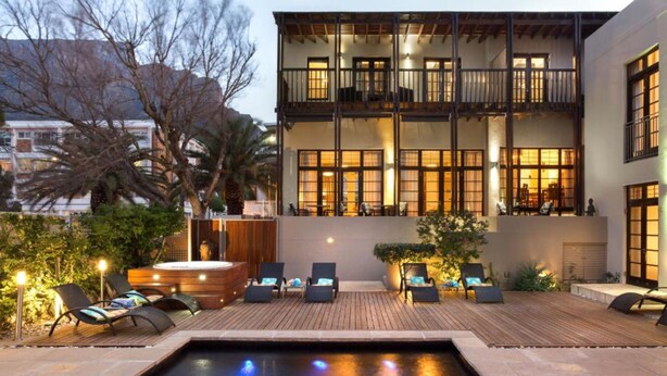 A two-story building with a rooftop deck, outdoor seating area, and a swimming pool. - Derwent House (Cape Town)