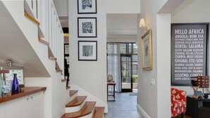 A staircase with wooden steps and white walls, leading to a room with a large window and a globe on a side table. - Derwent House (Cape Town)