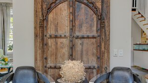 A room with a large wooden door, two leather chairs, and a small table with a decorative object. - Derwent House (Cape Town)