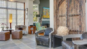 A spacious living room with a large wooden door, comfortable seating, and a fireplace. - Derwent House (Cape Town)
